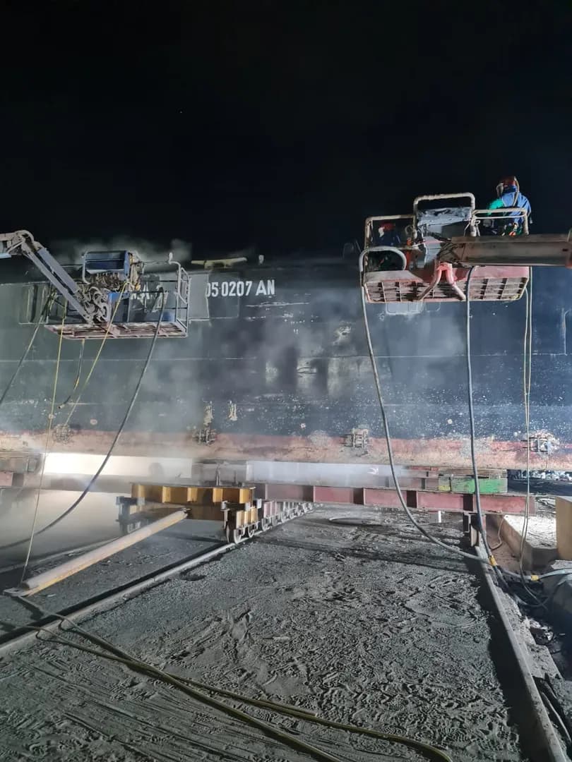 Operario en manlift durante sandblasting en astillero